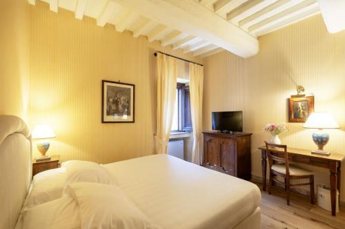 a bedroom with a bed and a desk and a television at Relais Il Canalicchio Country Resort & SPA in Canalicchio