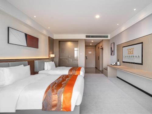 a hotel room with two beds and a television at Guanghan Exhibition International Hotel in Guanghan