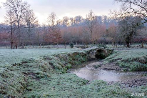 a bridge over a river in a field with snow at Maison privative dans un environnement idyllique in Lasne