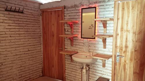 ein Badezimmer mit einem Waschbecken und einem Spiegel an einer Backsteinwand in der Unterkunft Indonesia Backpacker Hostels in Kuta Lombok