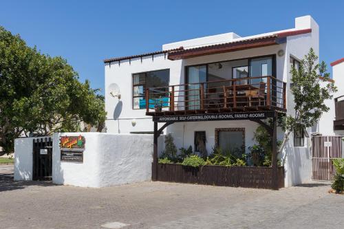 a white building with a balcony on top of it at Aloe Again in Jeffreys Bay