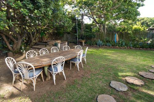 a long wooden table and chairs in a yard at Aloe Again in Jeffreys Bay