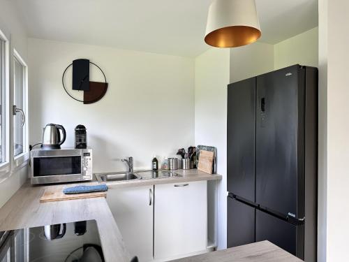 La cuisine est équipée d'un réfrigérateur noir et d'un évier. dans l'établissement L'Opale - Plain Pied - Acces PMR, à Les Attaques
