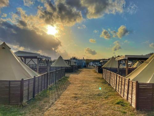 a row of tents behind a fence with the sun at Neo Grand in Minamiboso
