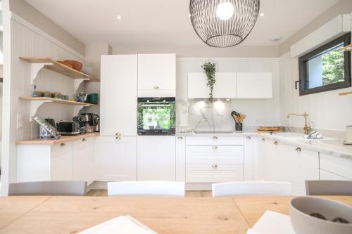 une cuisine avec des placards blancs et une lampe pendant dans l'établissement Belle villa moderne sous les pins au Moulleau, à La Teste-de-Buch