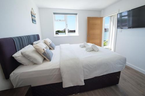 a bedroom with a bed with white sheets and pillows at Surfside Penthouse in Bournemouth
