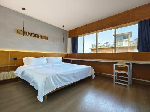 a bedroom with a white bed and a large window at West Street Hills Travel B&B in Quanzhou