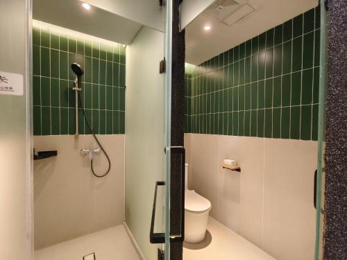 a bathroom with a shower and a toilet and green tiles at West Street Hills Travel B&B in Quanzhou