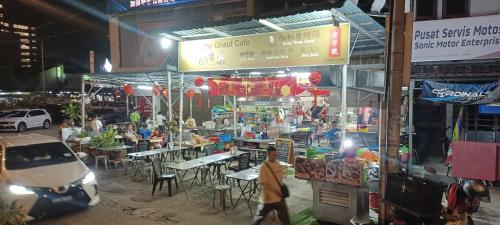 a market with tables and chairs on a street at night at LS Iconic Regency #Queensbay Mall#FIZ#Airport in Bayan Lepas
