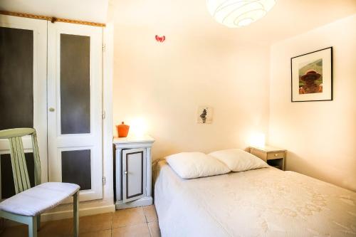 a small bedroom with a bed and a chair at Le mas du Four a Chaux in Gordes