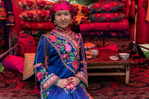 a woman in a blue dress sitting in a store at Arista Yurt Camp in Karakol