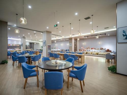 a restaurant with blue chairs and tables in a cafeteria at Guanghan Exhibition International Hotel in Guanghan
