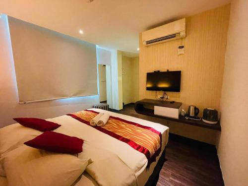 a hotel room with a bed and a television at The Riverfront Hotel in Melaka