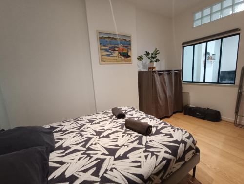 une chambre avec un lit avec une couette noire et blanche dans l'établissement Appartement calme proche de la mer, à Dunkerque