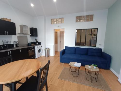 un salon avec un canapé bleu et une table dans l'établissement Appartement calme proche de la mer, à Dunkerque