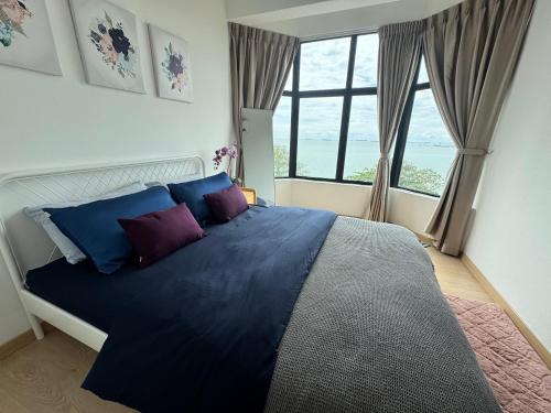a bedroom with a large bed with blue and purple pillows at 2BR Apartment - Beachfront - Corner Unit - Netflix - Unifi 300mbps - Mutiara Melaka Pantai Puteri in Malacca