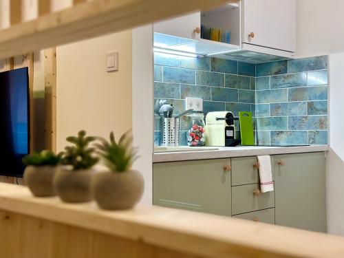 a kitchen with white cabinets and blue tiles on the wall at Colorful Condo by the Danube ---FREE PARKING--- in Budapest
