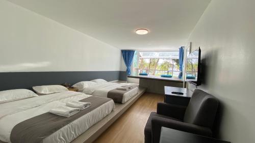 a bedroom with two beds and a chair and a window at BIDONG VIEW RESORT in Kuala Terengganu