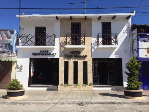 a white building with two balconies on a street at Hotel Tres Marías in San Cristóbal de Las Casas