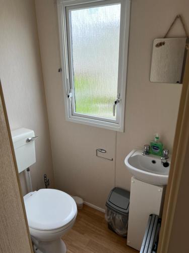 a small bathroom with a toilet and a sink at Chrissys Caravan in Mablethorpe