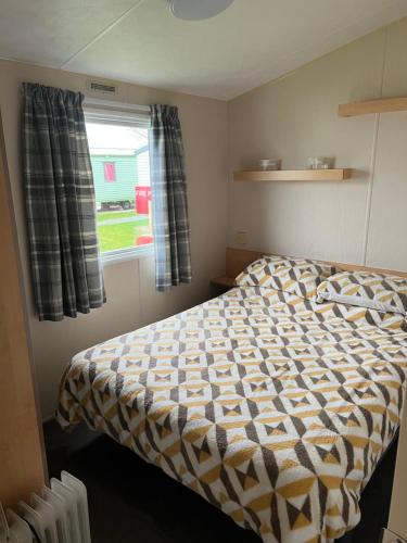 a small bedroom with a bed and a window at Chrissys Caravan in Mablethorpe