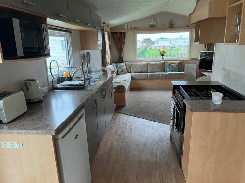 a kitchen and living room with a couch at Chrissys Caravan in Mablethorpe