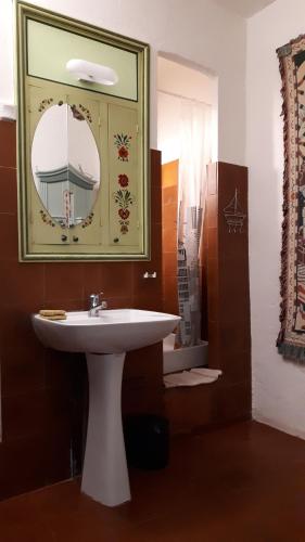 une salle de bain avec un lavabo blanc et un miroir dans l'établissement U Paisolu, maison de village en Corse, entre mer et montagne, à Nessa