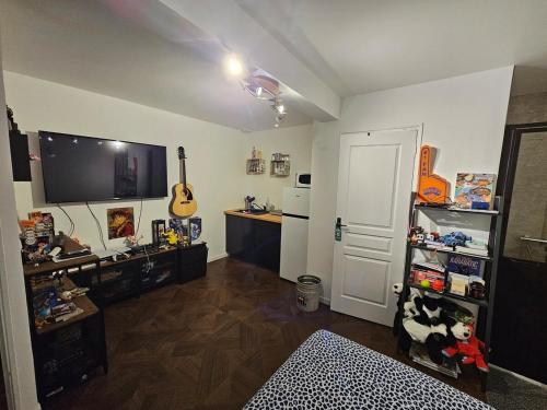 - un salon avec une télévision et une guitare sur le mur dans l'établissement Chez Isa et Geo le studio Jules, à Laguian-Mazoux