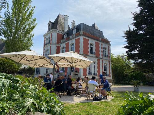 un groupe de personnes assises sous les chaises devant un bâtiment dans l'établissement Pleine vue mer et plage, à Larmor-Plage