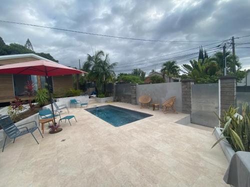 a backyard with a swimming pool and a patio with chairs at O coeur de l ouest Studio les Orangers in Saint-Paul
