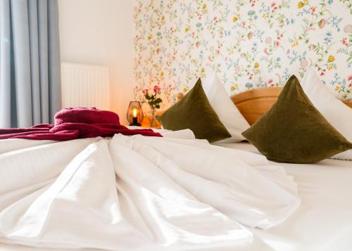a bed with white sheets and green pillows at Hotel Krone Tirol in Reutte