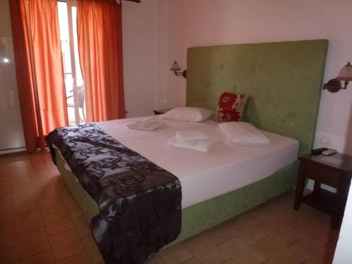 a bedroom with a bed with a green headboard at Galini Studios in Benitses