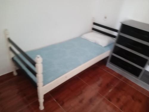 a small bed in a room with a wooden floor at Casa Balneário Picarras SC in Piçarras