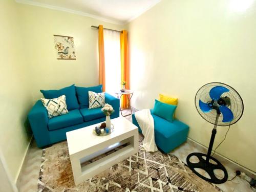 a living room with a blue couch and a fan at Beautiful, affordable 1bdrm in Milimani in Kisumu