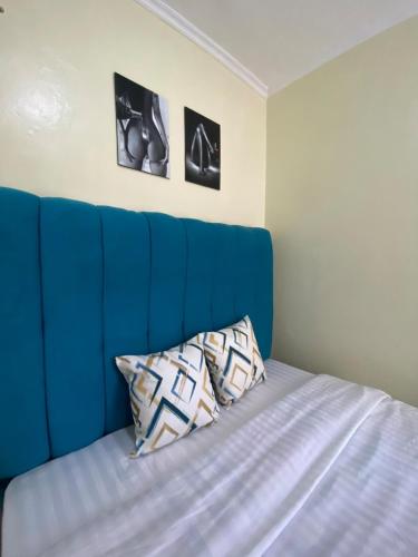 a bed with a blue headboard in a room at Beautiful, affordable 1bdrm in Milimani in Kisumu