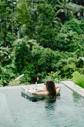 a woman laying in a bath tub in a swimming pool at Magical Jungle Resort in Ubud