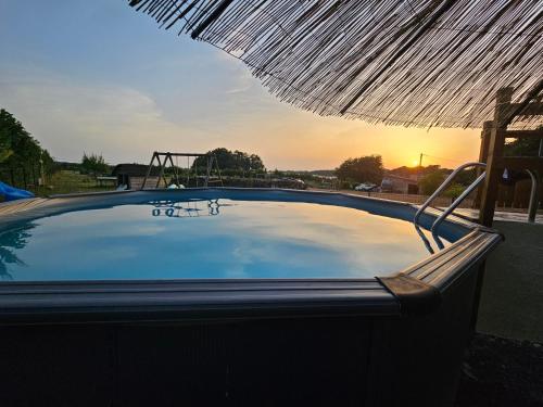 a large swimming pool with an umbrella and a playground at L'Escale -Domaine Des Boissons - in Meursac