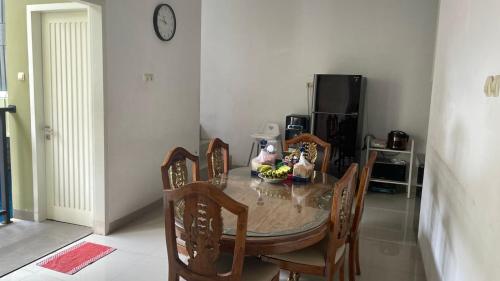 a dining room table with chairs and a clock on the wall at Griya Kania Arjuna in Ngaglik