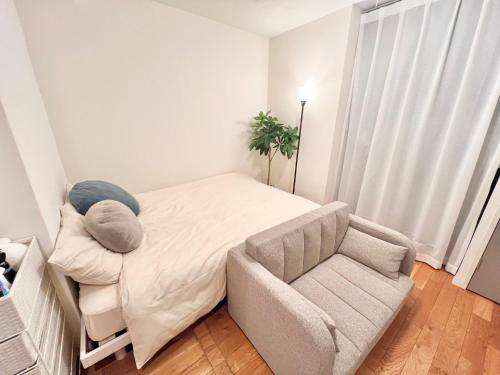 a small bedroom with a bed and a chair at FARE Akihabara - Stylish Spacious Studio 8min from Station 201 in Tokyo