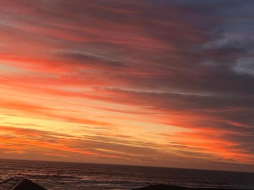 a sunset over the ocean with a cloudy sky at Sea Glimpse Yzer in Yzerfontein