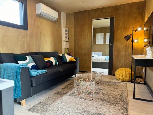 un salon avec un canapé noir et une table dans l'établissement Maison A avec air de jeux et jacuzzi, à Yvias