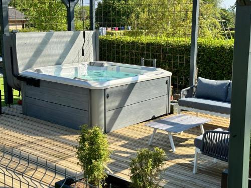 un bain à remous sur une terrasse avec une chaise et un banc dans l'établissement Maison A avec air de jeux et jacuzzi, à Yvias
