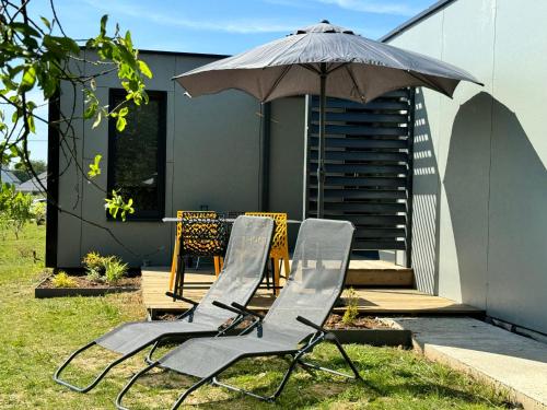 quelques chaises et une table avec un parasol dans l'établissement Maison A avec air de jeux et jacuzzi, à Yvias