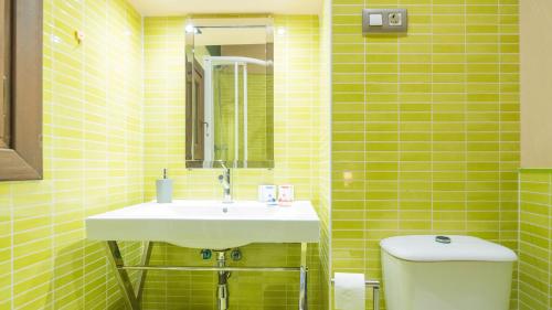 a yellow tiled bathroom with a sink and a toilet at Apartamento Pozo Amargo Junto a la Catedral by Toledo AP in Toledo
