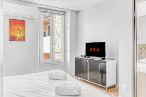 une chambre blanche avec un lit et une télévision dans l'établissement F3 Riouffe , Hypercentre à 2minutes du Palais des Festivals, à Cannes