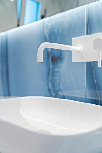 a white sink in a bathroom with a blue wall at Frunze Luxury Apartments in Nafplio
