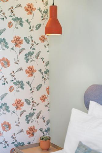 a lamp on a nightstand next to a wall with floral wallpaper at Frunze Luxury Apartments in Nafplio