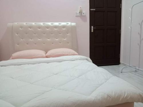 a white bed with pink pillows in a bedroom at Waseem Homestay Kuala Terengganu in Kuala Terengganu