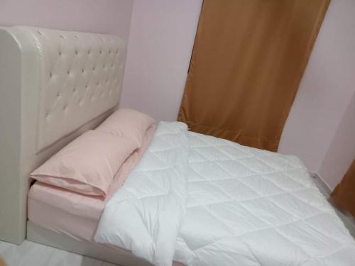 a bed with white sheets and pillows in a room at Waseem Homestay Kuala Terengganu in Kuala Terengganu