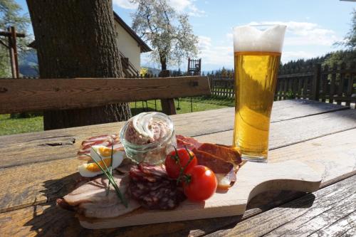 a plate of food and a glass of beer on a wooden table at Ferienwohnungen Lichtenegger in Kamp